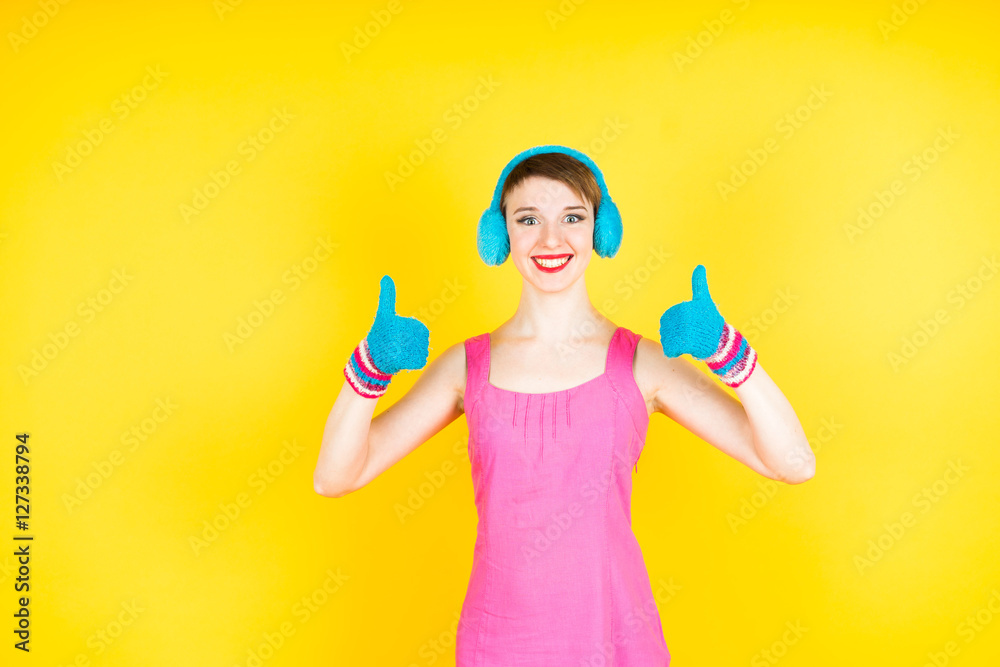 Smiling woman showing big thumbs in gloves. Isolated on yellow background. Smiling woman showing big thumbs in gloves. Isolated on yellow background.