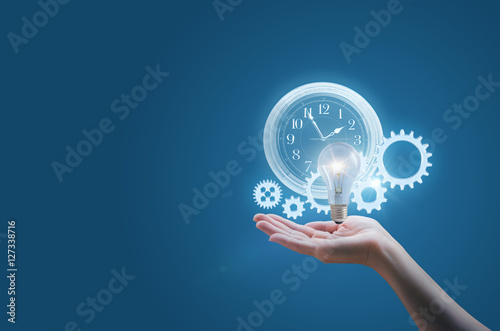 Business woman in the hand of a clock gears and the lamp symbolizes the effective implementation of business ideas