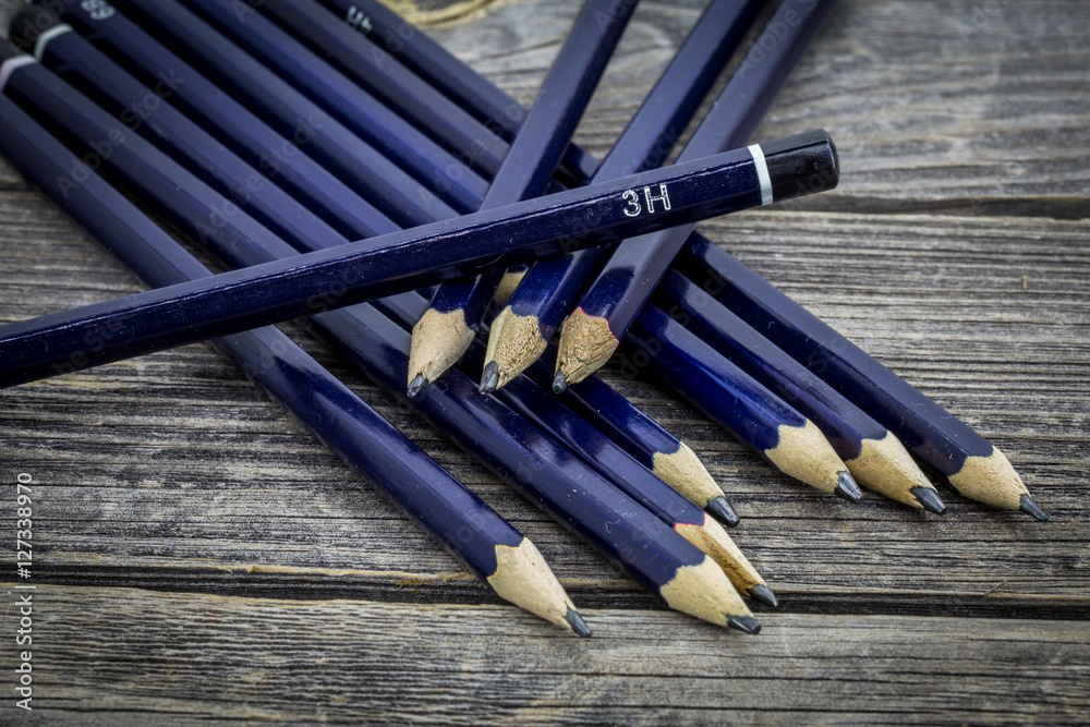 set of black pencils on wooden background set of black pencils on wooden background