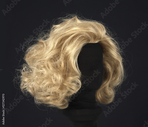 blonde feminine wig on black background and textile mannequin. photo
