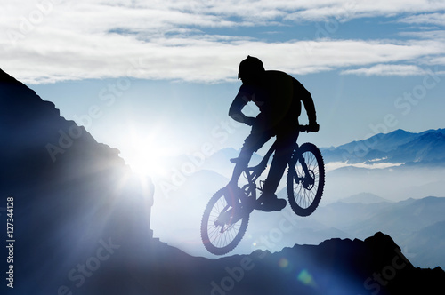 Photo springender Mountainbiker im Gebirge im Gegenlicht