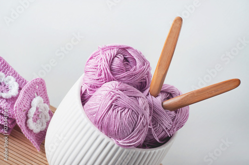 Balls of cotton yarn in pink with crocheted afghan squares