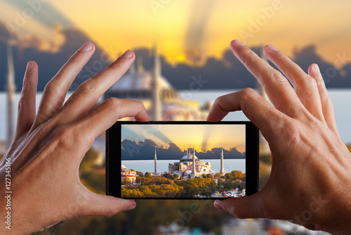 Travel concept. Hands making photo of night city with smartphone camera. Istanbul at sunset. Turkey