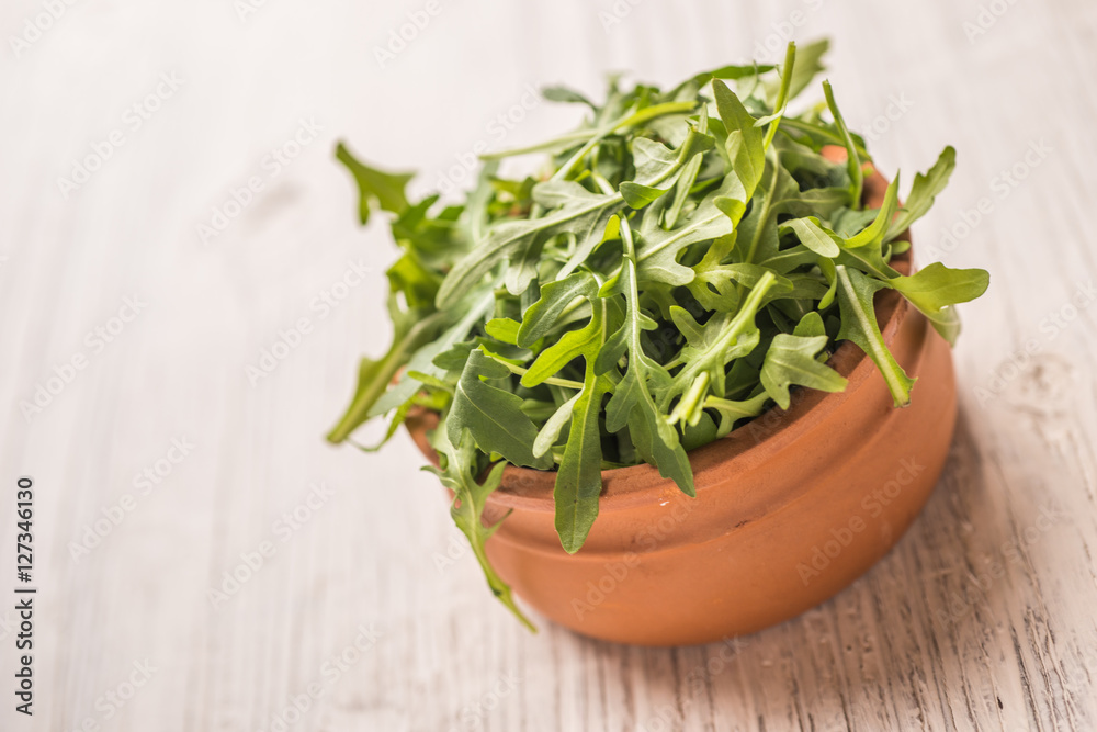Fresh green arugula in bowl on wooden table Fresh green arugula in bowl on wooden table