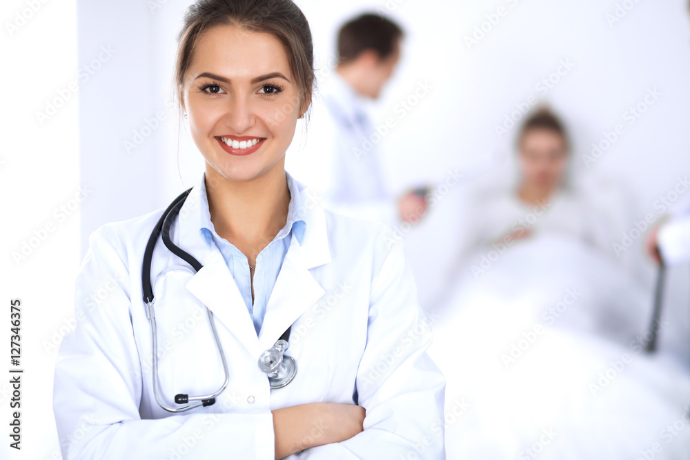 Female doctor smiling on the background with patient in the bed Female doctor smiling on the background with patient in the bed