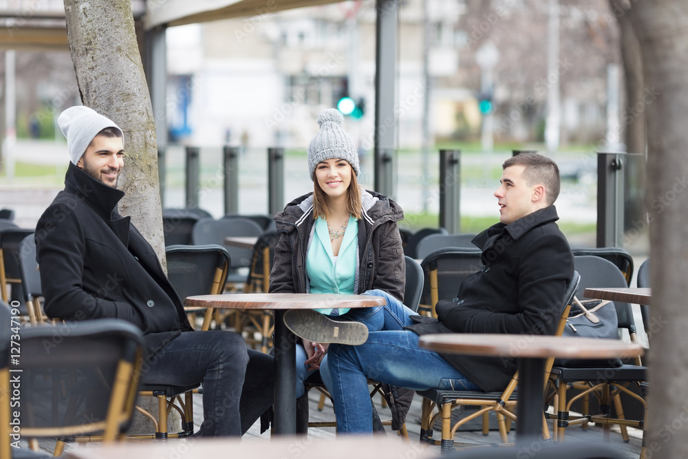 Group of young friends is resting in an outdoor caffe.