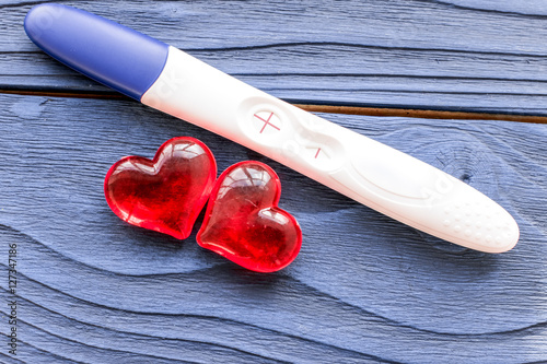 Positive pregnancy test with heart on wooden background top view