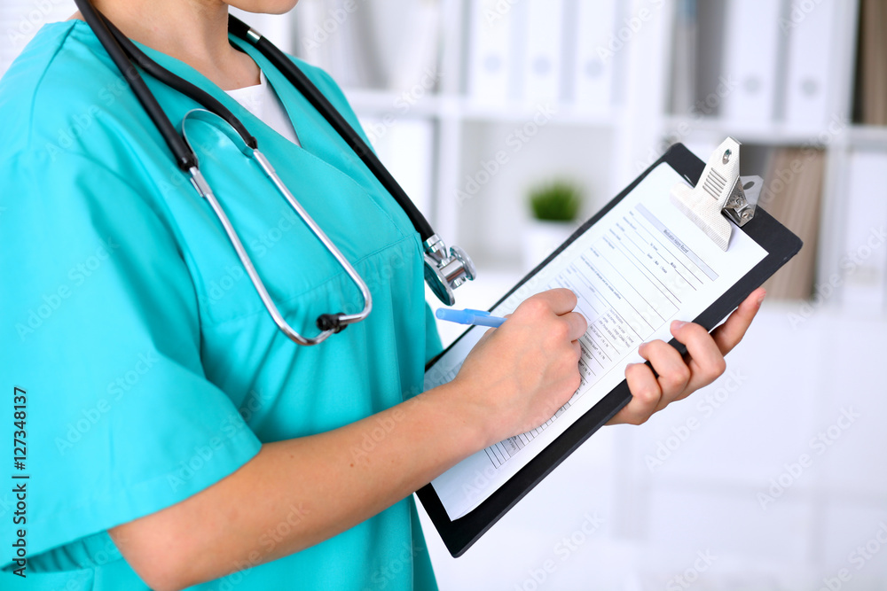 Close-up of a female doctor is filling out application form or medical history Close-up of a female doctor is filling out application form or medical history