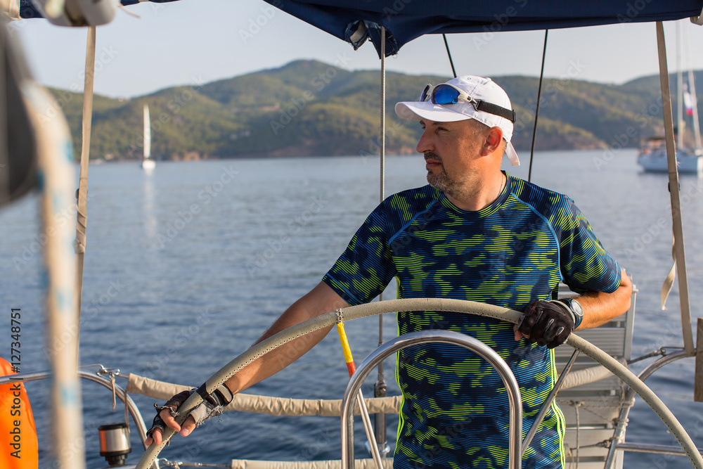 Fototapeta premium Man skipper steers sailing boat on the Sea. Luxury yacht..