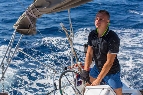 A man controls a sailing ship boat during sea yacht race.