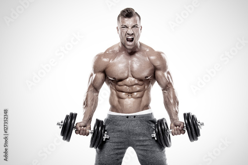 Muscular bodybuilder guy doing exercises with dumbbell