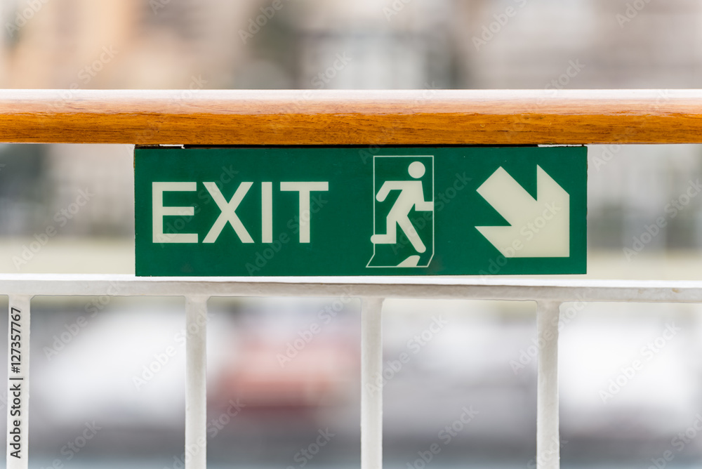 Attention green Exit sign with arrow on wooden railing cruise ship Attention green Exit sign with arrow on wooden railing cruise ship