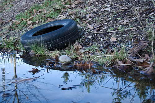 Old car tire lying next to a puddle