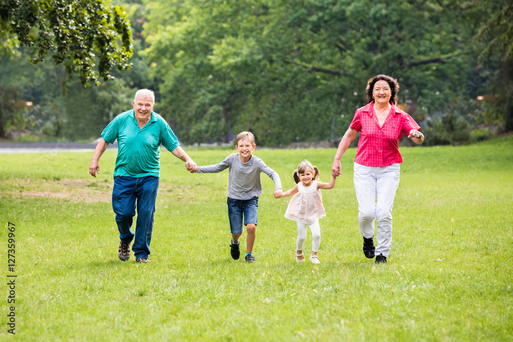 Grandparents And Grandchildren Running In Park Grandparents And Grandchildren Running In Park