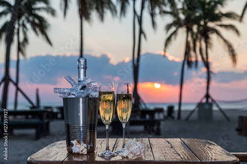 New Year Celebration at beach/New Years Eve celebration background with pair of flutes and bottle of champagne in bucket.


