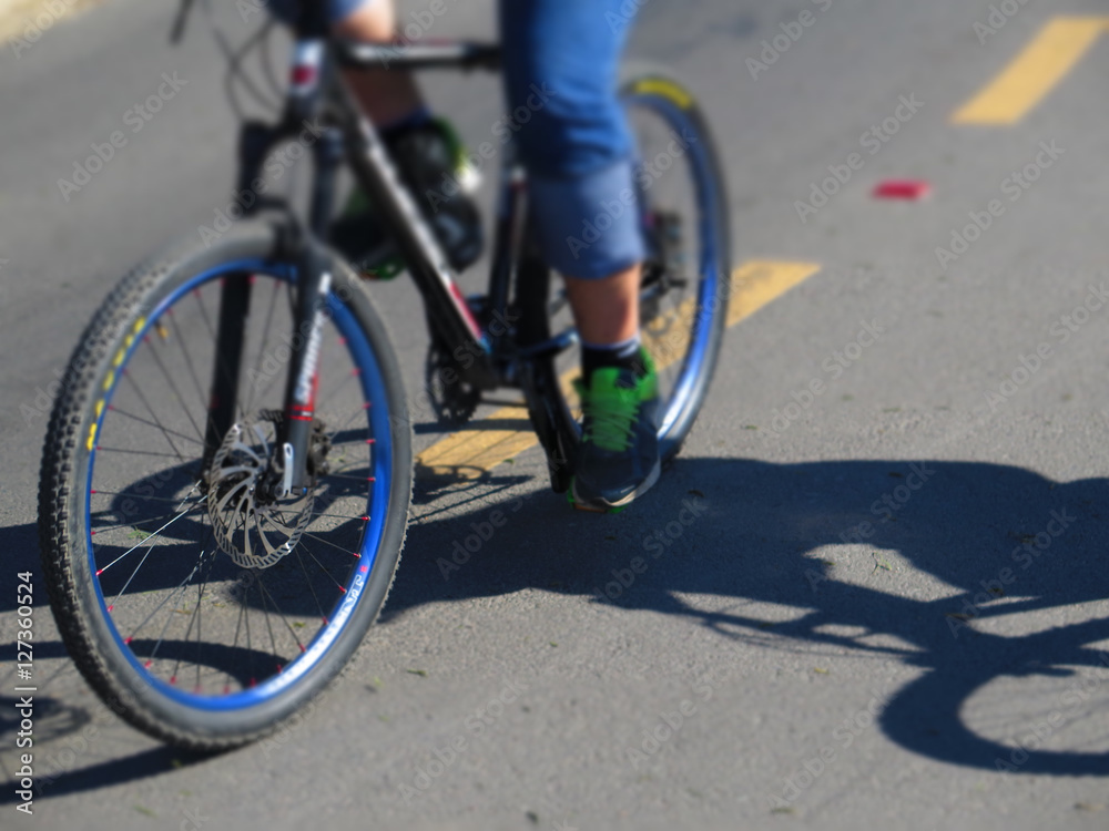 low angle view of cyclist riding mountain bike on asphalt trail low angle view of cyclist riding mountain bike on asphalt trail