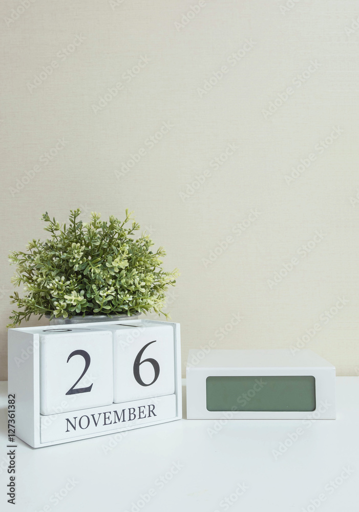 White wooden calendar with black 26 november word with clock and plant on  white wood desk and cream wallpaper textured background , selective focus  at the calendar Stock Photo | Adobe Stock