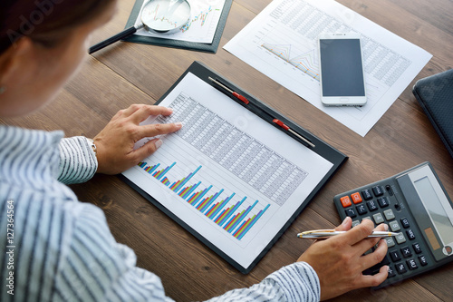 Business analysis - calculator, sheet, graphs (business report) and analyst hand, top view photo