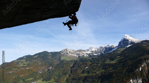 a mountain climber aid climbing a gigantic roof in the Swiss Alps