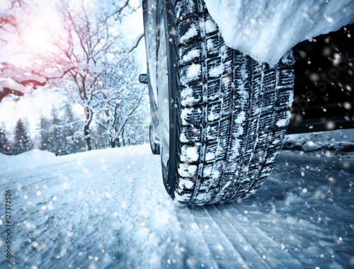 Car tires on winter road covered with snow. Vehicle on snowy alley in the morning at snowfall © candy1812