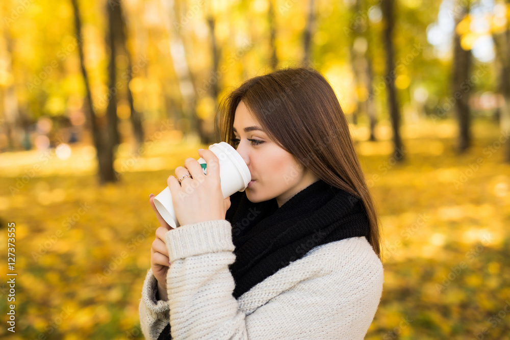 Young girl drink coffee in autumn yellow sunny park Young girl drink coffee in autumn yellow sunny park
