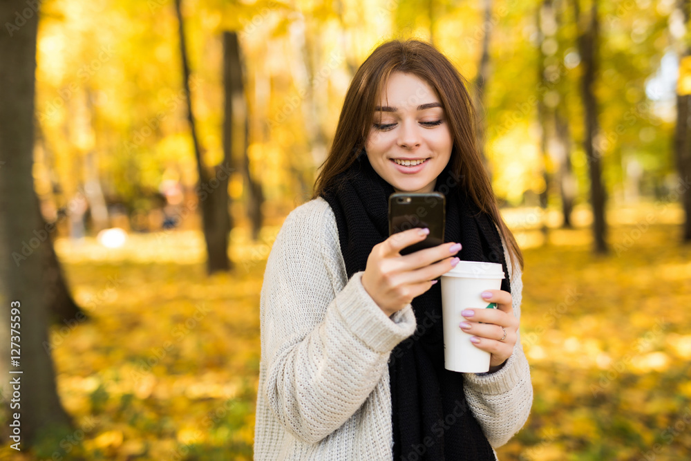 Young girl taking selfie on phone with coffee on yellow sunny park Young girl taking selfie on phone with coffee on yellow sunny park