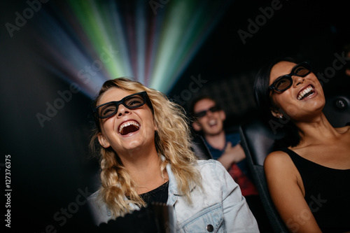 Smiling female friends watching 3d movie