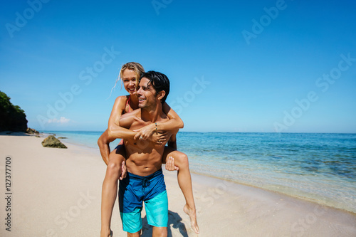 Happy young couple piggyback on tropical beach © Jacob Lund