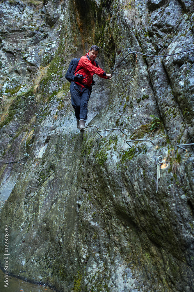 Man hiker climbing mountain walls