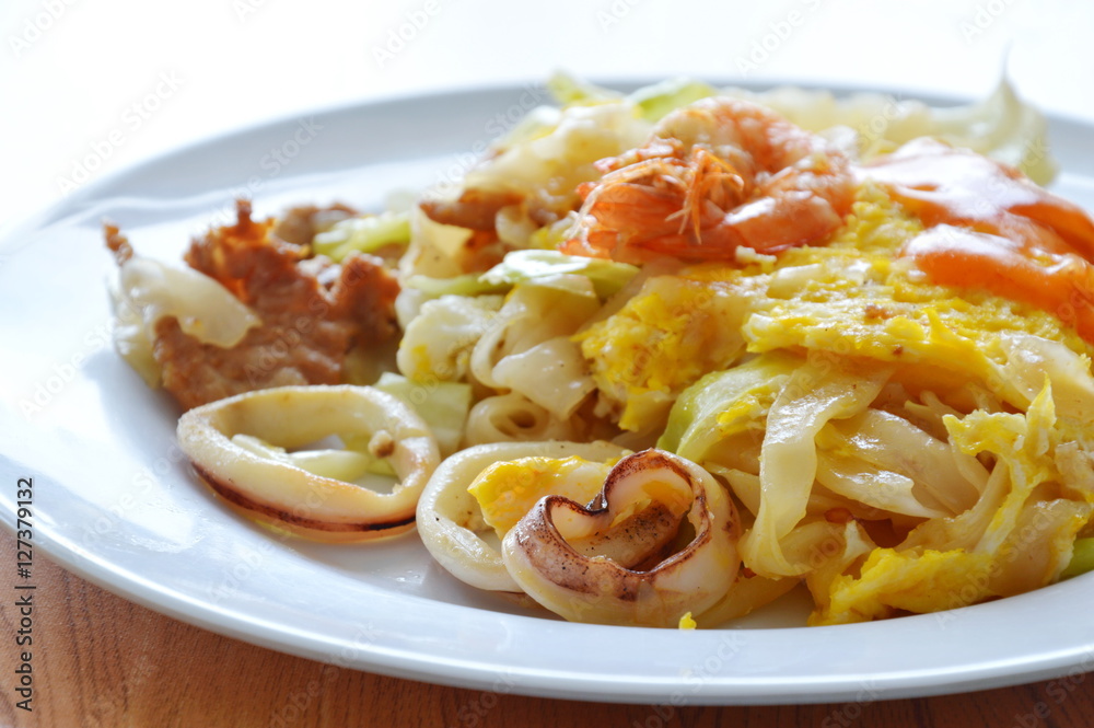 stir fried rice noodle seafood and egg with cabbage dressing chili on dish stir fried rice noodle seafood and egg with cabbage dressing chili on dish