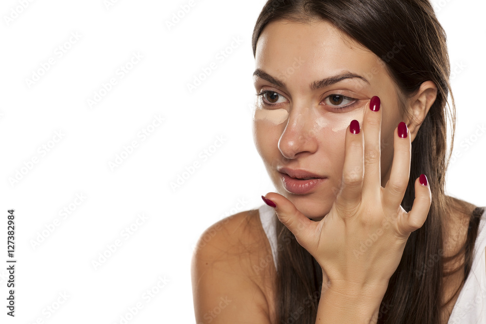 Fototapeta premium young women applied concealer under the eyes with her finger