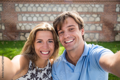 Couple taking selfie with smartphone. Beautiful young couple por