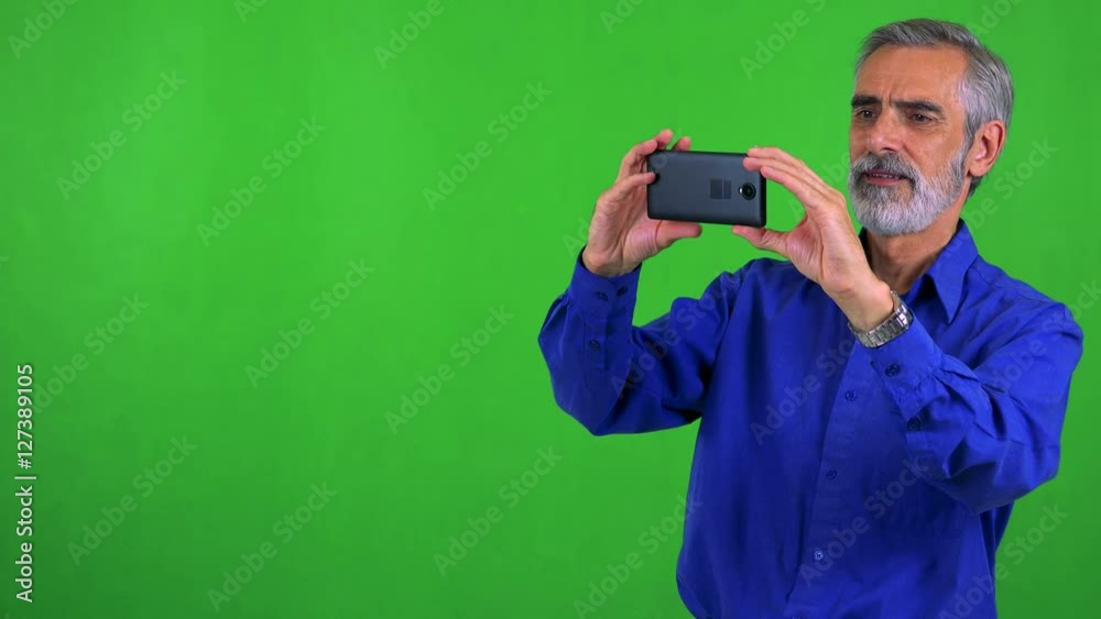 old senior man takes photos with smartphone - green screen - studio old senior man takes photos with smartphone - green screen - studio