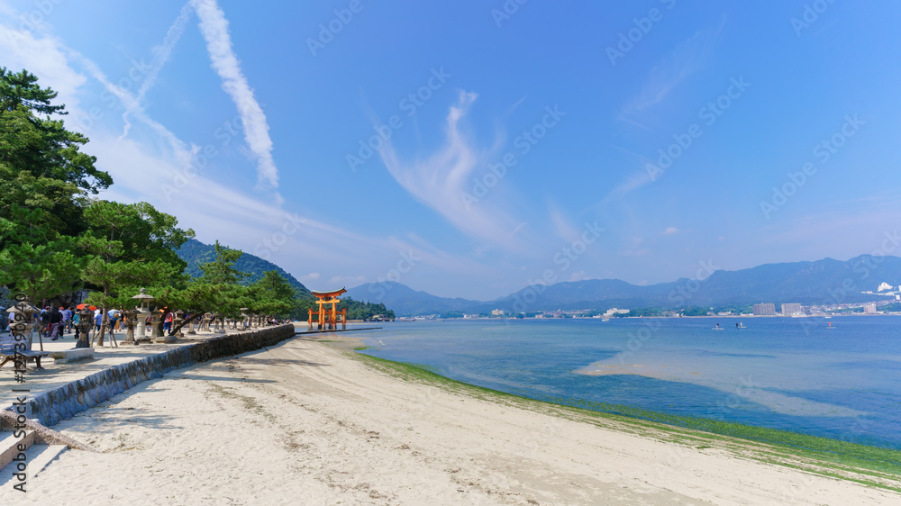 Fototapeta premium Scenery of sea coast on Miyajima Island viewing the famous orange floating Japanese shinto gate (Torii) of Itsukushima shrine in the bay 