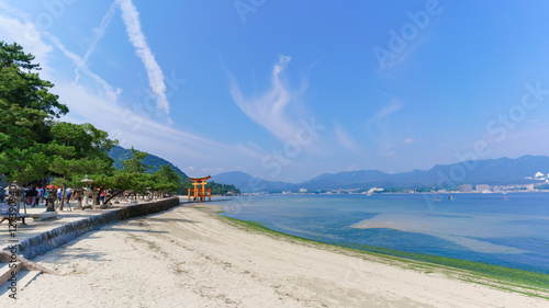 Scenery of sea coast on Miyajima Island viewing the famous orange floating Japanese shinto gate (Torii) of Itsukushima shrine in the bay  photo
