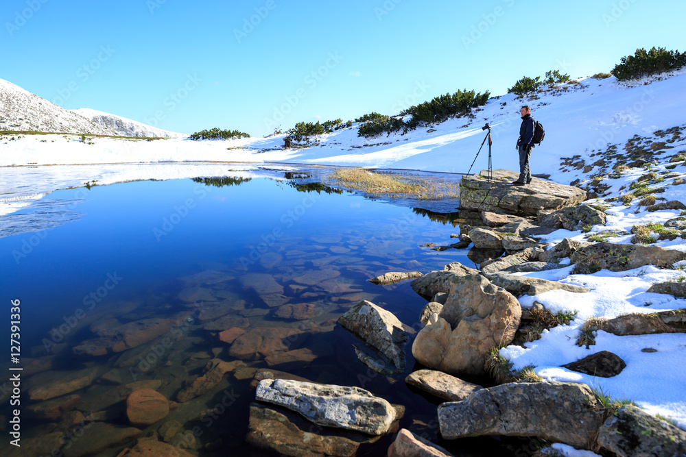 Photographer taking photos of beautiful landscape in the mountain lake. Winter lake. Travel inspiration and motivation, beautiful landscape.