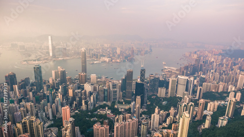 Beautiful aerial shot of many high skyscrapers covered with sunset fog or haze in Hong Kong  China. Top view of Victoria Harbour from Victoria Peak at sunset. City skyline.