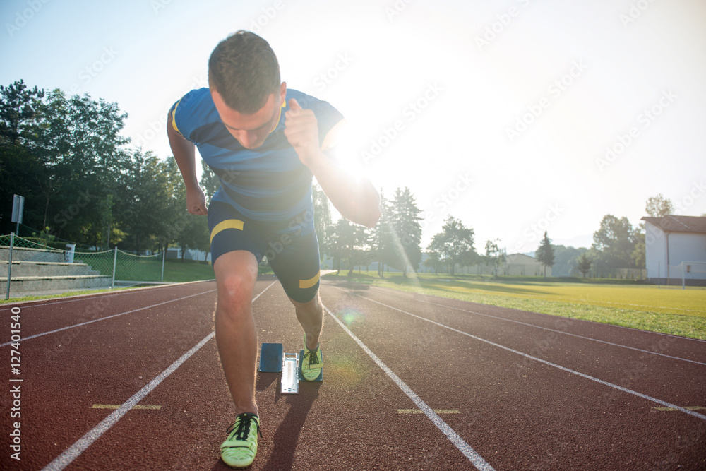 Obraz premium Sprinter leaving starting blocks on the running track. Explosive start.