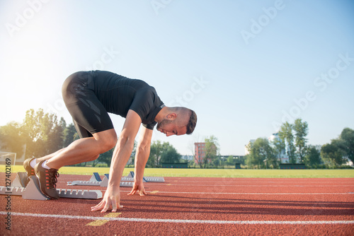 Male athlete on starting position at athletics running track. © FS-Stock