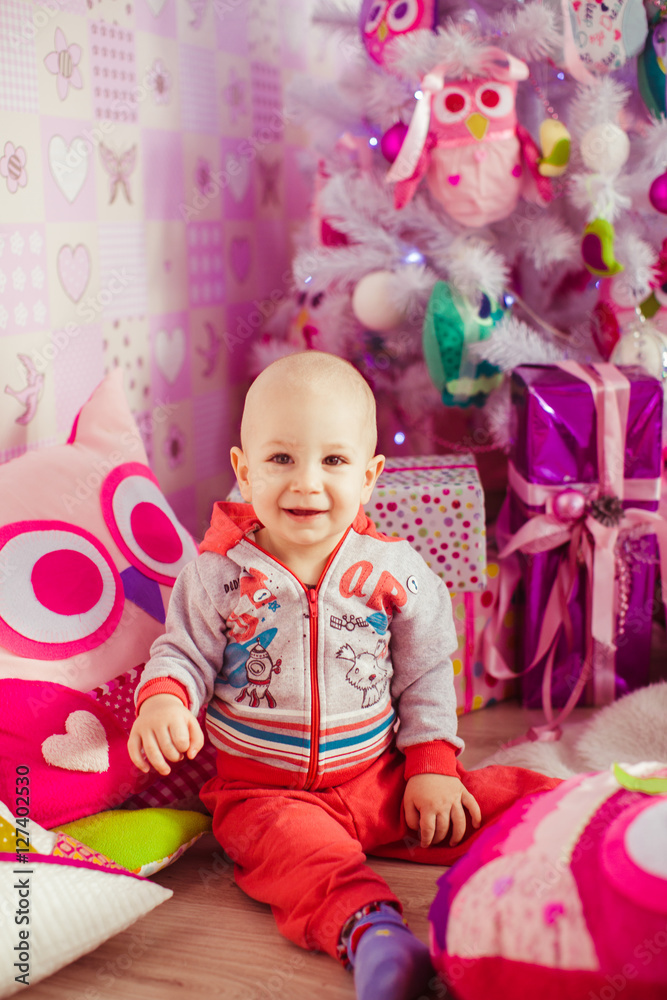 little smiling child sitting on the floor near the Christmas tre little smiling child sitting on the floor near the Christmas tre