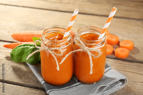 Jars with carrot smoothie on wooden background