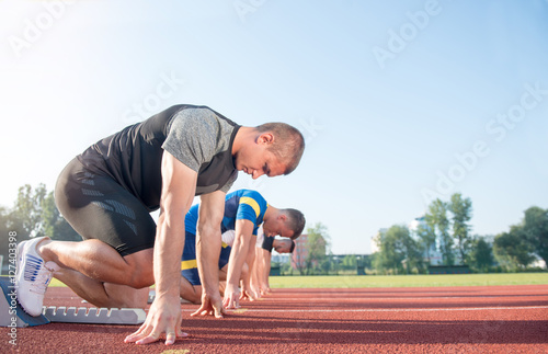 Close-up side view of cropped people ready to race on track field