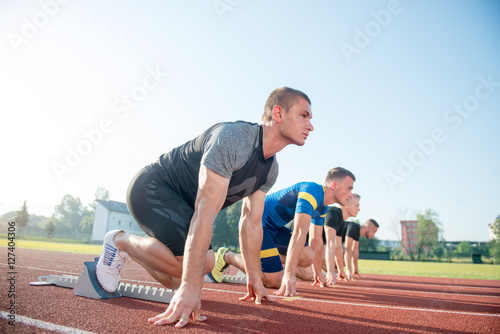 Close-up side view of cropped people ready to race on track field