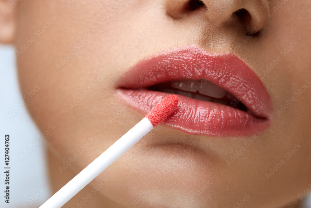 Naklejka premium Beauty Makeup. Beautiful Woman Applies Lip Gloss