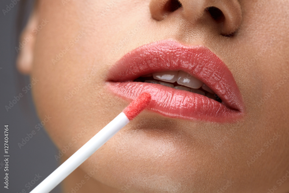 Naklejka premium Beauty Makeup. Beautiful Woman Applies Lip Gloss