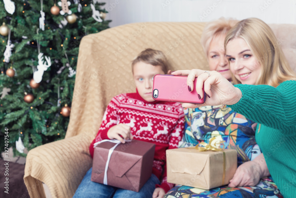 Happy family taking picture with smartphone on Chistmas decorations. Selective focus on smartphone Happy family taking picture with smartphone on Chistmas decorations. Selective focus on smartphone