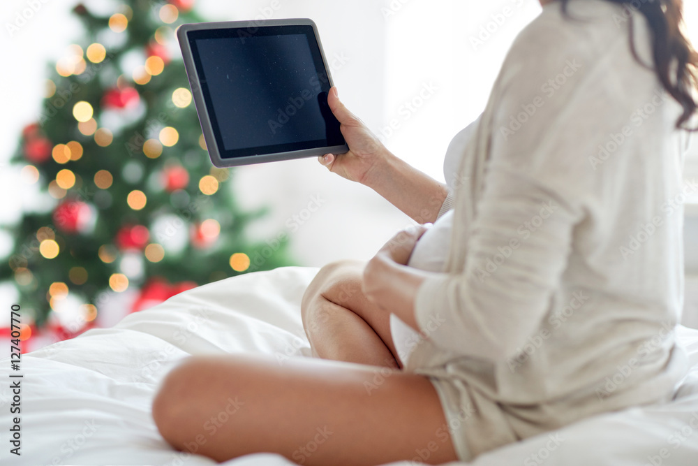 Naklejka premium close up of pregnant woman with tablet pc at home