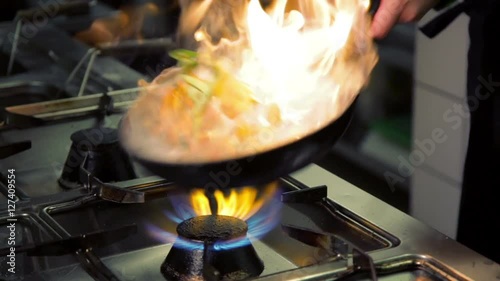 chef cook holding pan and doing flambe
