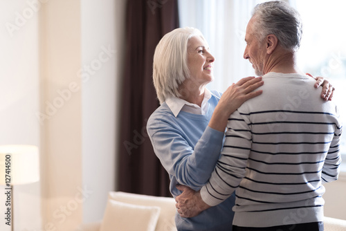 Cheerful aged couple hugging each other at home © zinkevych