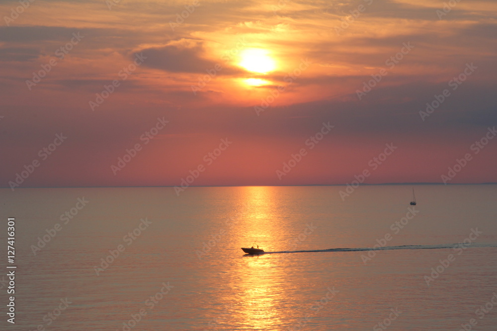 silhouettes of boats, yachts, ship on the background of sunset, sunrise, yellow, orange sky at sea
